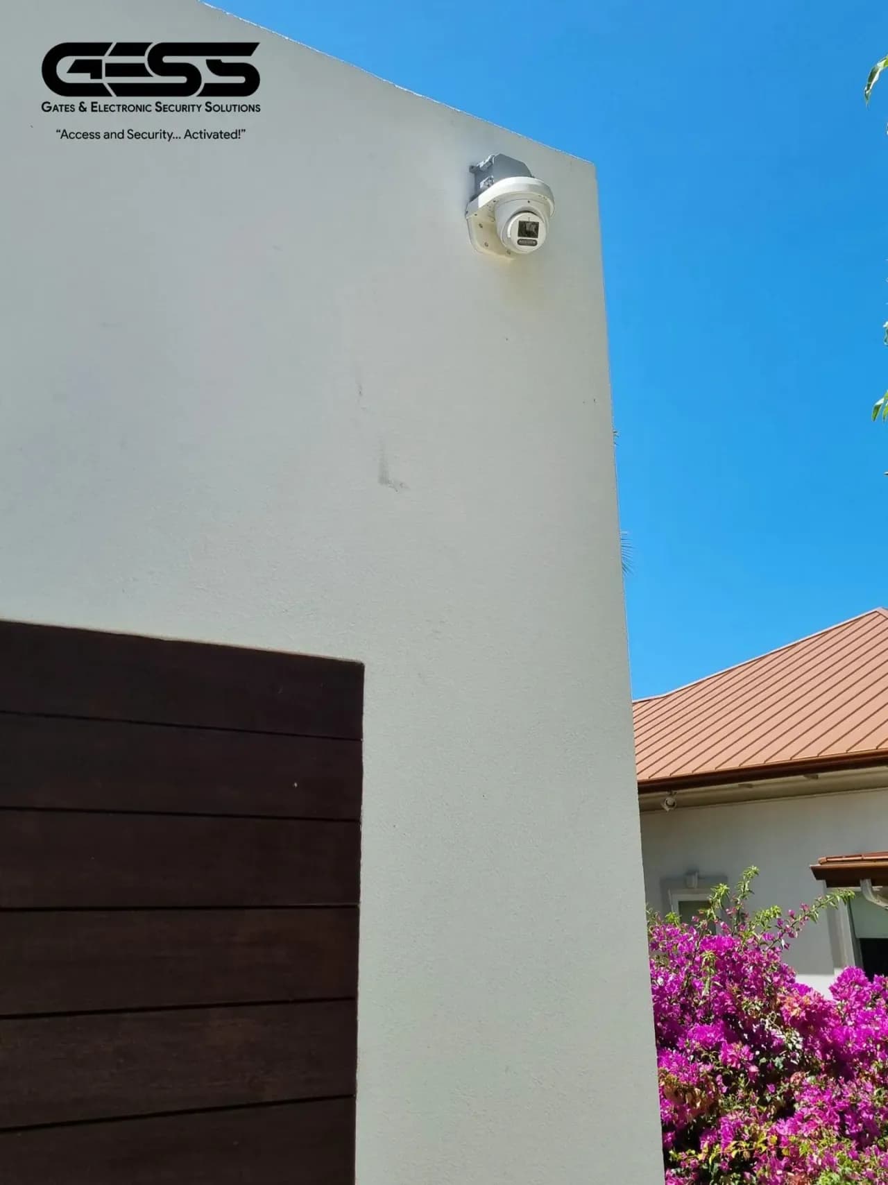 White turret camera mounted high on a rendered exterior wall