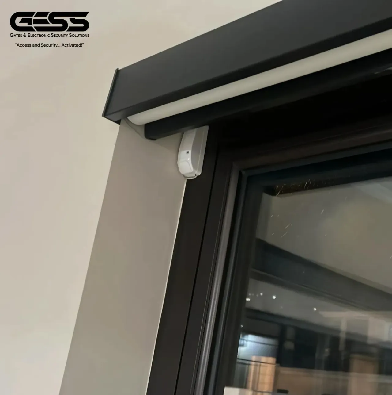 White magnetic contact sensor fitted at the top of a patio door frame