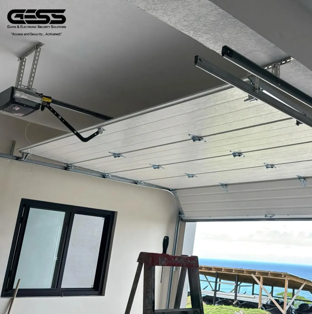 Overhead garage opener and rail bracketed to a ceiling above a fitted door