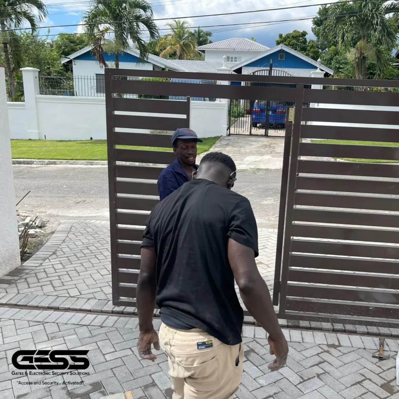 Two GESS team members setting a brown slatted driveway gate