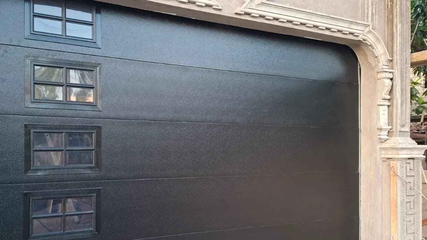 Black insulated sectional garage door fitted to a Jamaican home